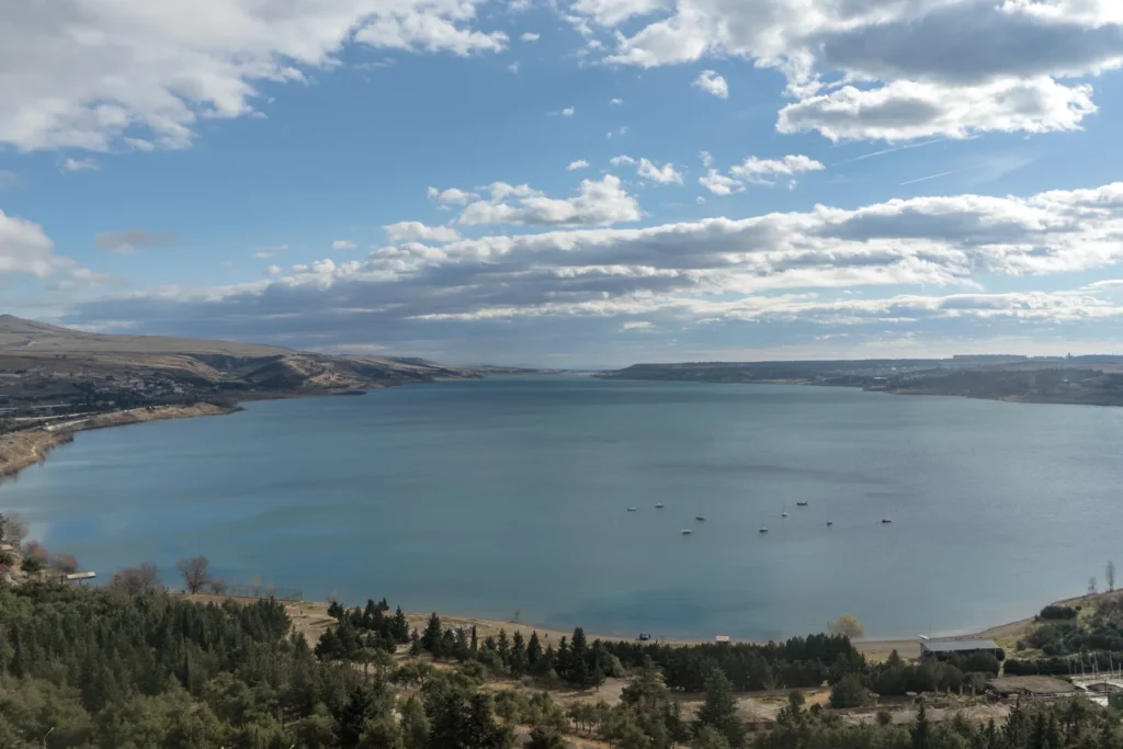 Sailboats on Tbilisi Sea beneath a wide, cloud-filled sky.